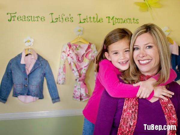 Mom and room designer Janice Peters with her daughter in front of a wall design with butterflies and flowers and hooks to hang clothing. The wall says Treasure Life's Little Moments.