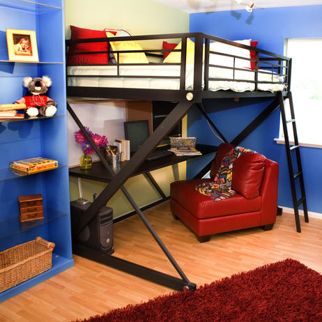 This child's bedroom gets a red and blue color scheme by designer Tori on this challenge of Design Star on HGTV. A red chair with a computer desk sits under the bunk bed, with shelving, and an art easle to the side.